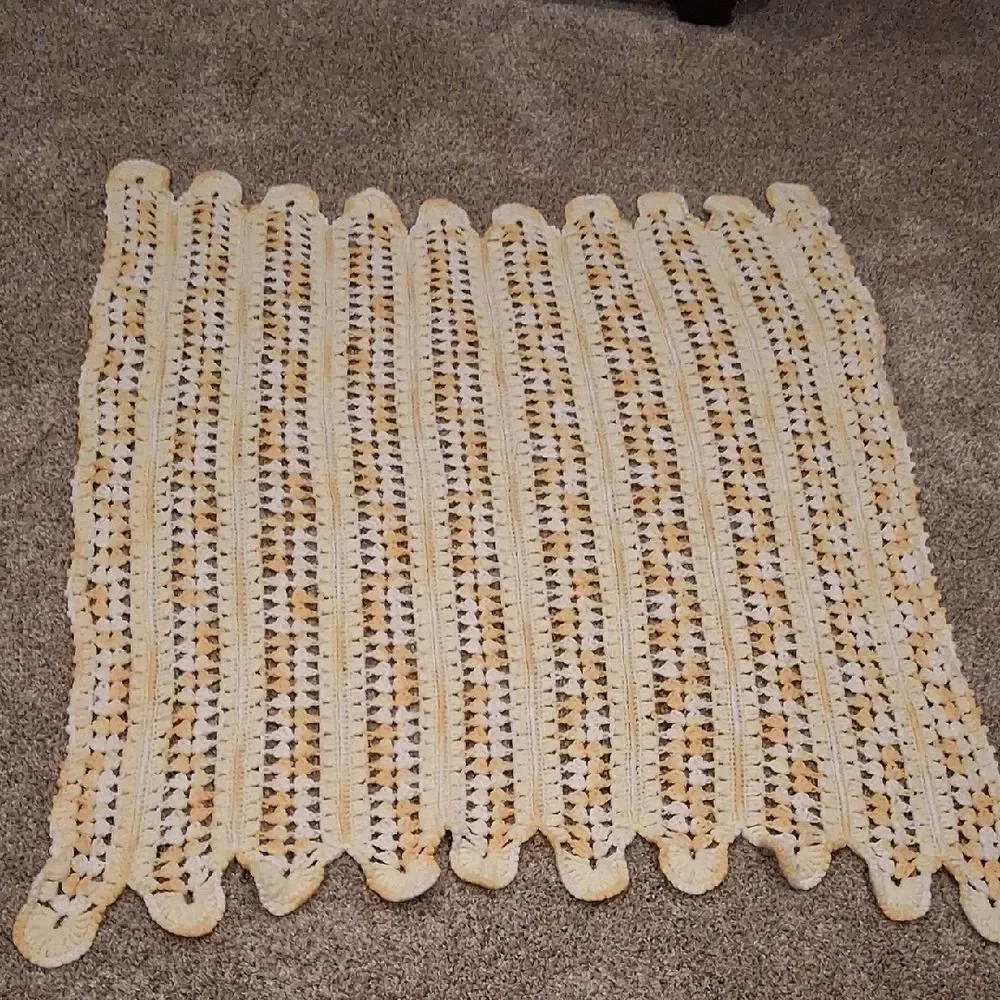 Handmade yellow and white crocheted baby blanket with a scalloped edge